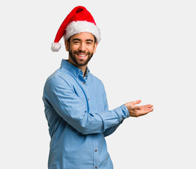 Young man wearing santa hat holding something with hands