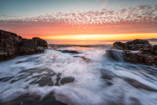 Stormy sea with colorful sunrise sky at the rocky coastline of the Black Sea