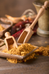Indian spices with wooden spoons on a wooden table.