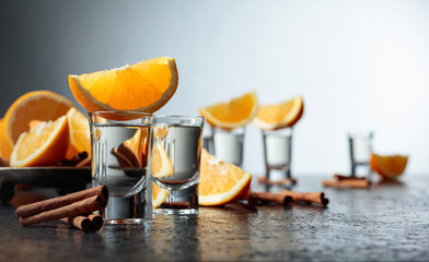 Glasses of tequila with orange and cinnamon sticks.