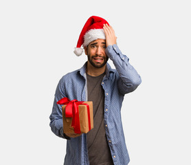 Young man wearing santa hat forgetful, realize something
