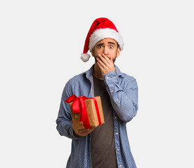 Young man wearing santa hat very scared and afraid hidden