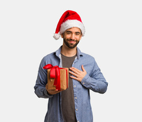 Young man wearing santa hat doing a heart shape with hands