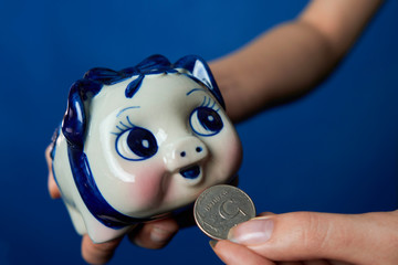 piggy money box gets coin, blue background