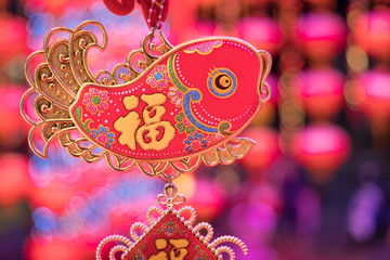 chinese symbol on fish decoration is hanging on with festival blur in background, the word mean luck