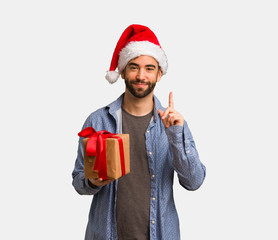 Young man wearing santa hat showing number one