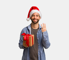 Young man wearing santa hat showing number three