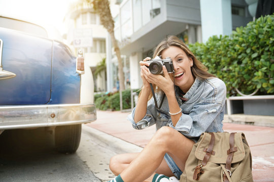 Attractive backpacker looking at vintage camera in city