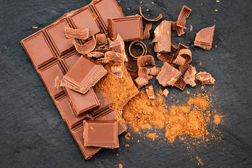 Broken chocolate pieces and cocoa powder on a dark background