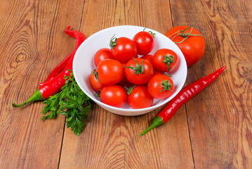 Red cherry tomatoes in white bowl and other vegetables