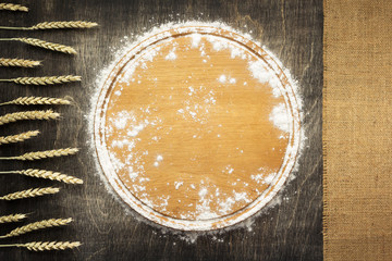 wheat flour and cutting board on wooden background