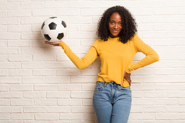 Young black woman holding something with hands, showing a product, smiling and cheerful, offering an imaginary object