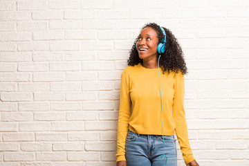 Young black woman looking up, thinking of something fun and having an idea, concept of imagination, happy and excited