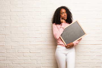 Young black woman thinking and looking up, confused about an idea, would be trying to find a solution