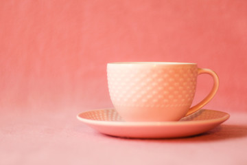 Fototapeta na wymiar Female lifestyle/business concept: pink coffee cup and plate, pink background, selective focus, free copy space