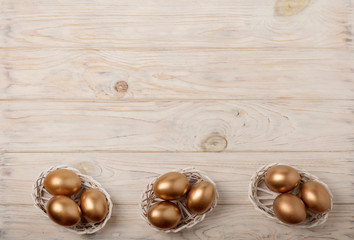 Happy easter! Easter decor and Easter eggs of golden color on a light wooden background.