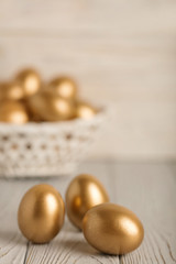 Happy easter! Easter eggs of golden color on a light wooden background.