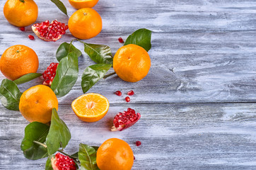 fruits, tangerines, pomegranate, leaves, on a wooden background with space for text