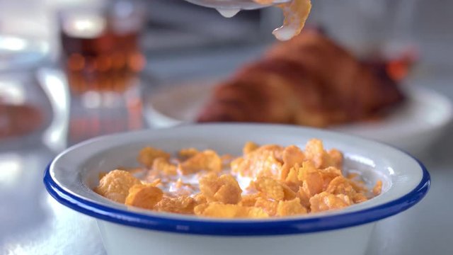 spoon takes away some cornflakes with milk from bowl full of corn flakes