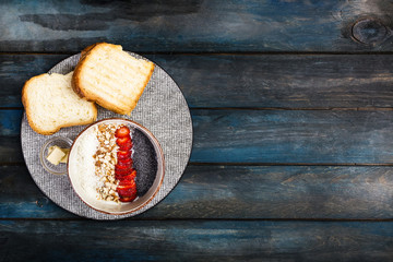 Healthy breakfast. Rice cereal or porridge with fresh strawberry, almond and coconut flakes, served with bread and butter. On a beautiful wooden background. Top view, copy space for your text