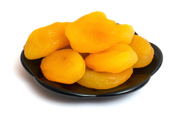 Dried apricots on a black plate, image on a white isolated background_