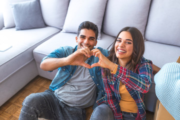 Happy couple during moving house showing heart sign
