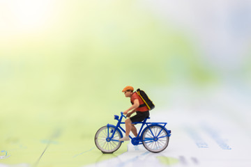 Miniature people : travel with bicycle on world map, cycling to destination on travel business background concept.