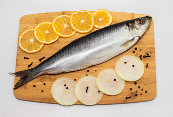 Herring on a cutting board with onions and lemon