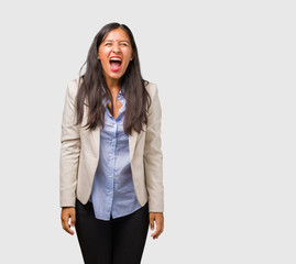 Young business indian woman screaming angry, expression of madness and mental instability, open...