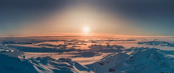 Foto op Plexiglas Heldere zonsondergang panorama-view in Antarctica. Oranje zonlicht over het met sneeuw bedekte polaire oppervlak. Pittoresk winterlandschap. De schoonheid van de wilde ongerepte Antarctische natuur. © Goinyk