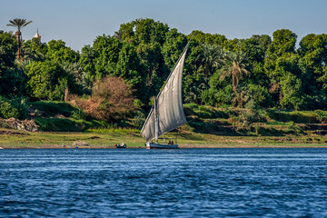 12.11.2018 Aswan, Egypt, A boat felucca sailing along the river nil on a sunny day against a shore beach