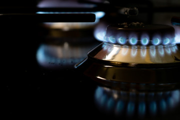 burning gas stove blue flames close up in the dark on a black background
