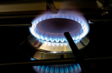 burning gas stove blue flames close up in the dark on a black background