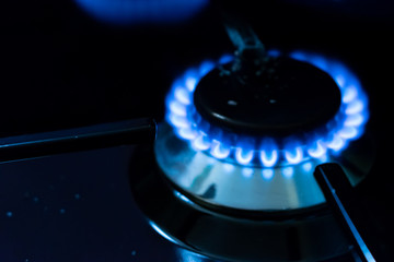 burning gas stove blue flames close up in the dark on a black background
