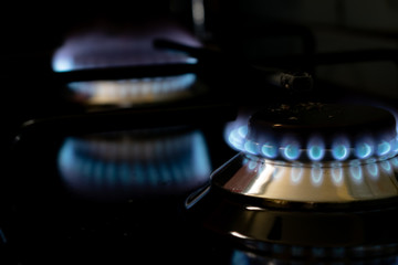 burning gas stove blue flames close up in the dark on a black background