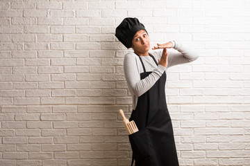 Young baker indian woman against a bricks wall tired and bored, making a timeout gesture, needs to stop because of work stress, time concept