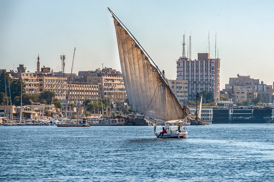 12.11.2018 Aswan, Egypt, A boat felucca sailing along a river of nilies on a sunny day against a city background