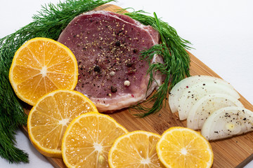 meat steak on a board with onion greens and lemon