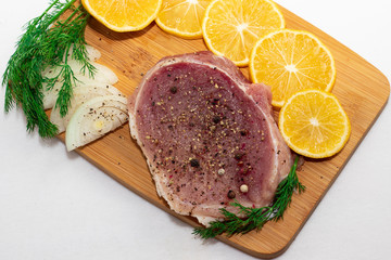 meat steak on a board with onion greens and lemon