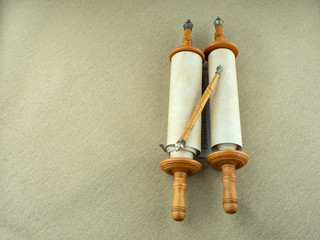 Torah scrolls with a wooden pointer on a rough canvas. Copy space.
