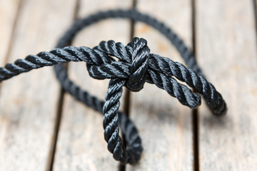 A bowline knot tied on a length of rope on a wooden background.
