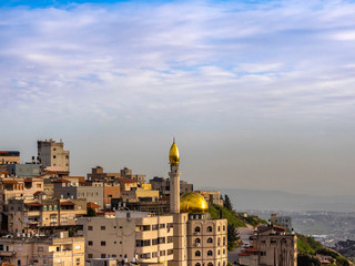 A mosque with a golden dome among the residential buildings in Nazareth.