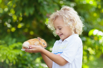 Fototapeta premium Dziecko z królikiem. Zajączek wielkanocny. Dzieci i zwierzęta.