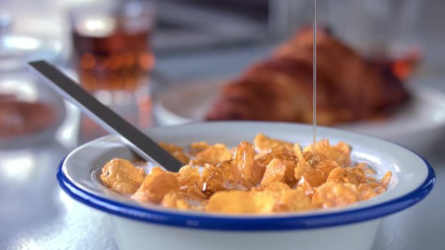 panned video how honey cover corn flakes in a bowl natural light