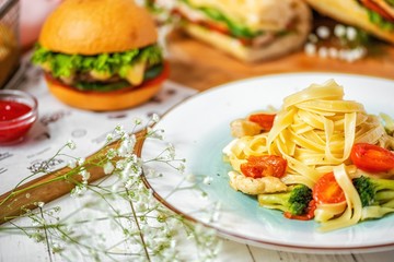delicious Italian pasta with chicken, broccoli and cherry tomatoes on a white plate