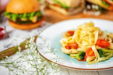 delicious Italian pasta with chicken, broccoli and cherry tomatoes on a white plate