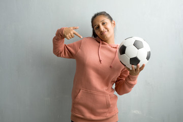 Young sporty indian woman against a wall proud and confident, pointing fingers, example to follow,...