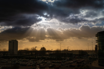 Naklejka premium Dramatic sky with rays of sun over city