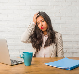 Young indian woman at the office worried and overwhelmed, forgetful, realize something, expression...