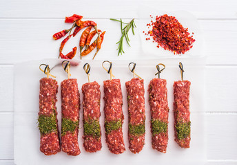 Raw kebab with spices on a white table